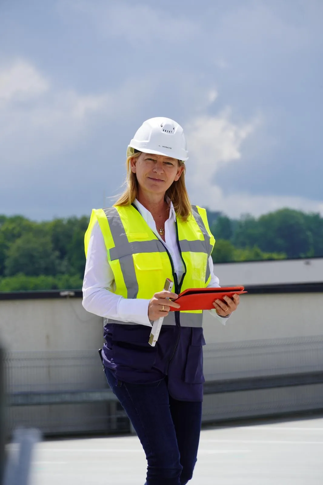 Bauingenieurin mit Helm und Tablet auf einem Dach